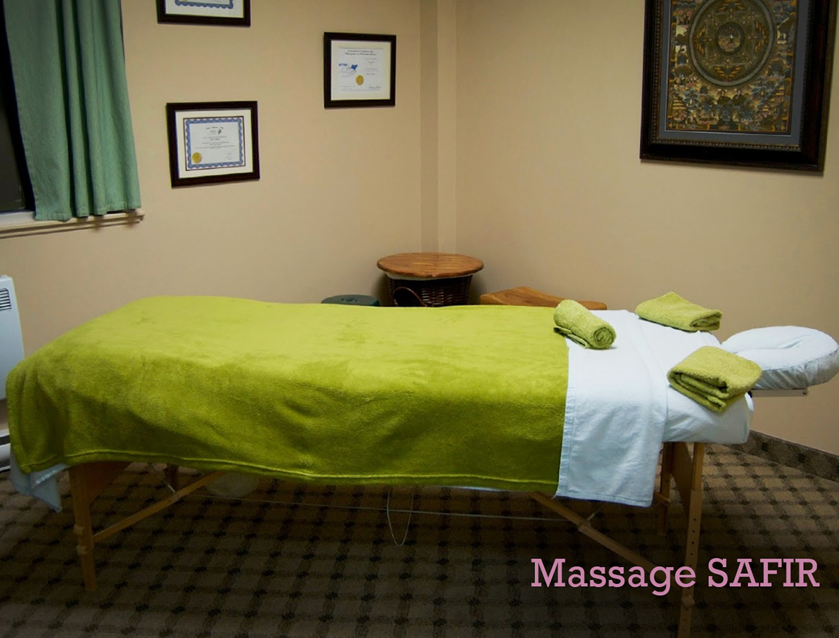 Massage table with green sheet in the middle of a warmly decorated room.